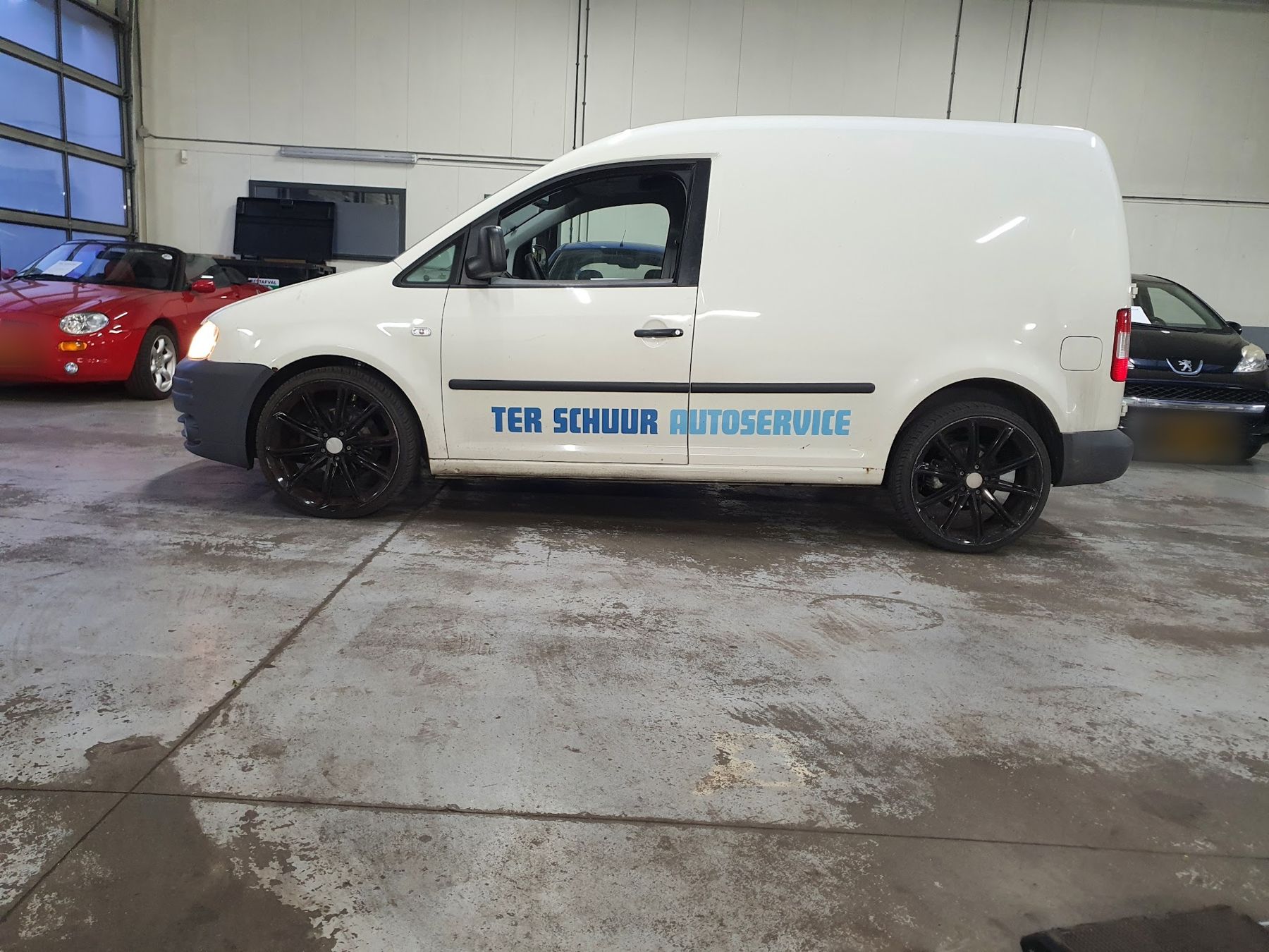 De witte bedrijfsbus met Ter Schuur Autoservice-belettering in de werkplaats